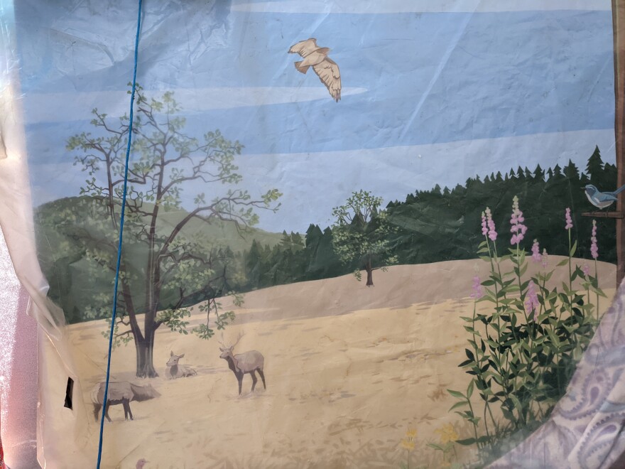 A painting of a nature scene featuring elk, wildflowers, hills, and forest.