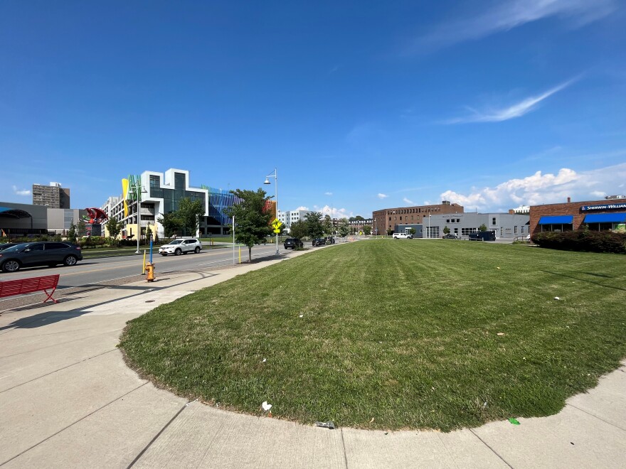 View of sidewalk wrapping around a small grassy lot