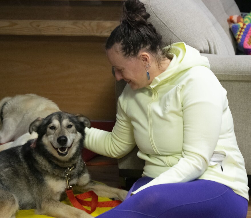 Yukon Quest veterinarian Kristine Preiser snuggles up to Moose, a dropped sled dog, at the Fort Yukon checkpoint on Feb. 11, 2026. (Herbert/KUAC)