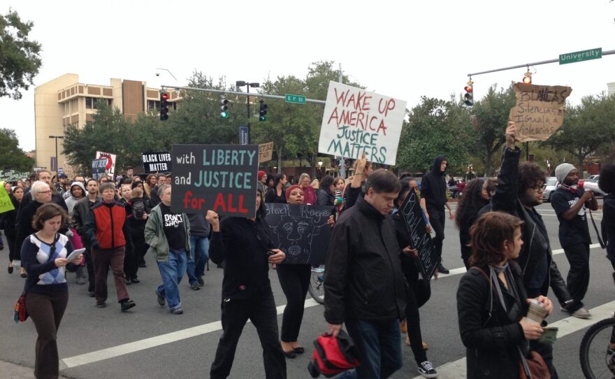 Protesters hold up signs and chant as they march down University Avenue. The march went the mile-long distance from downtown Gainesville to the intersection of University Avenue and 13th Street.