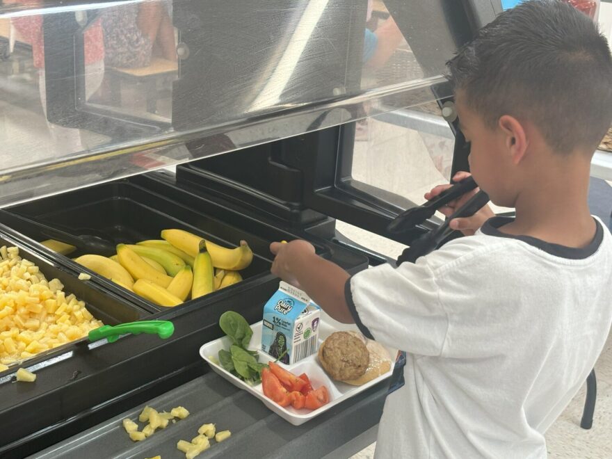 A Vista Grande Elementary student grabs a banana as part of lunch in the school cafeteria in Rio Rancho. (Photo courtesy of the New Mexico Public Education Department)
