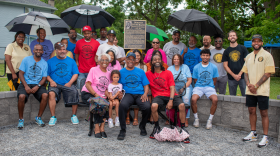 A group of people sit in front of a plaque dedicating the Southside park to Civil Rights icon, Dorothy Bacon