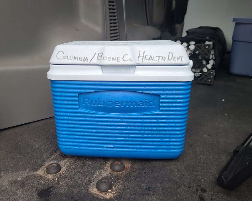 A small Rubbermaid cooler sits alone in the back of a van.