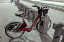 A snow covered Red Bike sits alone in a docking station along Mehring Way, in the predawn hours of January 19, 2024.