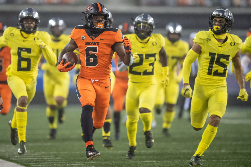 University of Oregon football players chasing an Oregon State ball carrier.
