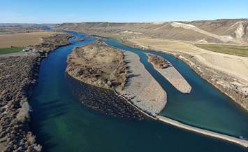 An island sits between two arms of a deep blue river which is surrounded by desert on the left and right.