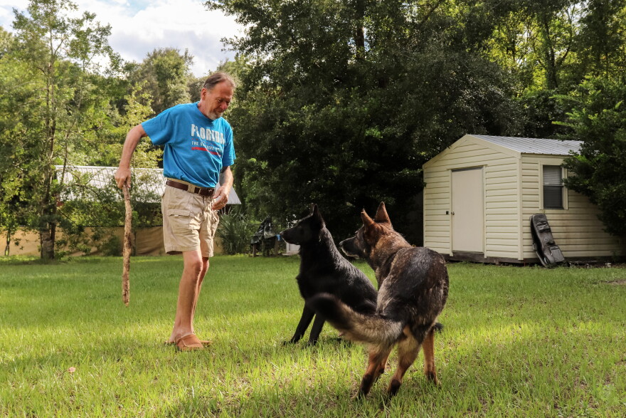 Now recovered from his stroke, Lothar Weimann, 68, plays with his two German Shepherds, Willy, left, and Ellie, right, in the backyard of his Gainesville, Fla., home on Sept. 16, 2021. 