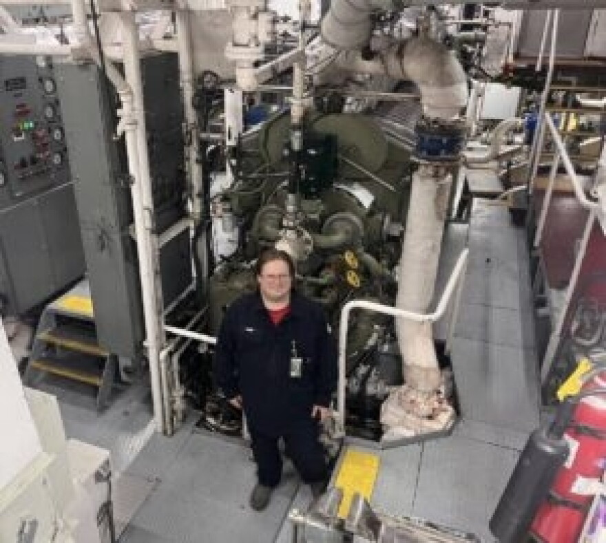Wearing earplugs, oiler Earl Clark stands beside one of the two engines of the ferry Tillikum.