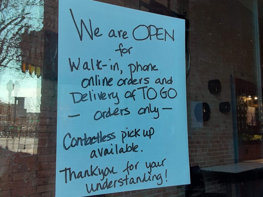 A sign in the window of a restaurant in Bozeman, Montana outlines service options during COVID-19, Apr. 9, 2020. 