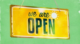 Yellow We Are Open sign on a green background.