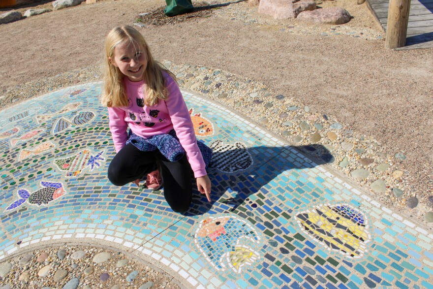 Lily Beal points out her fish on the mosaic.