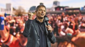 Former Cleveland Browns quarterback Bernie Kosar holds a microphone as he speaks to fans during the fourth round of the NFL football draft, May 1, 2021, in Cleveland.