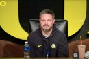 Head Oregon Football Coach Dan Lanning sits behind a microphone, ready to answer questions from the press. 