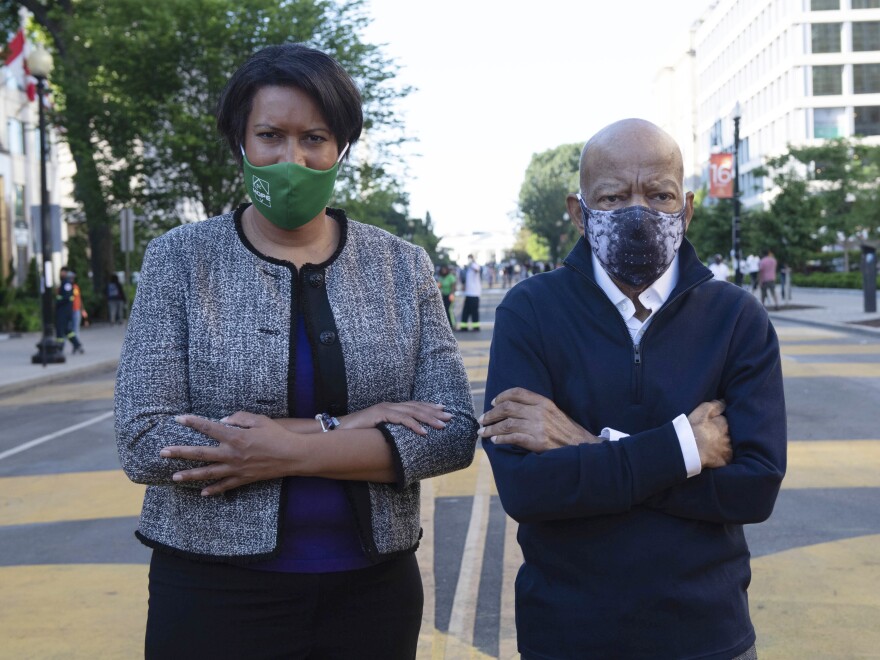 In this June 7 photo provided by the Executive Office of District of Columbia Mayor Muriel Bowser, the mayor and John Lewis look over a section of 16th Street that has been renamed Black Lives Matter Plaza in Washington. It would be Lewis' final public appearance.