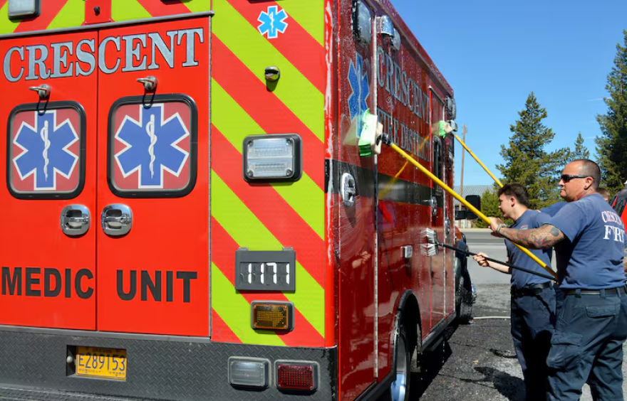 Two people washes an ambulance.