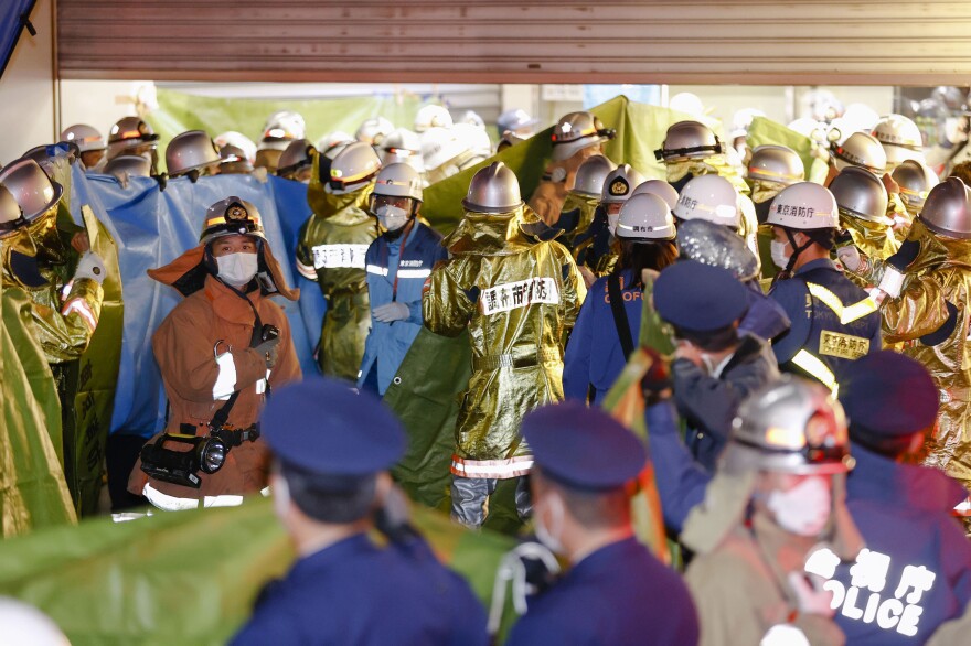 Emergency workers and police officers are seen at a train station in Tokyo on Sunday, after a man brandishing a knife on a commuter train stabbed several passengers before starting a fire.