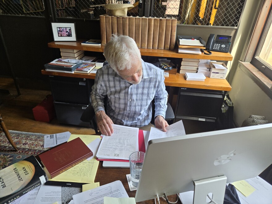 A man sits at a desk reading through handwritten letters