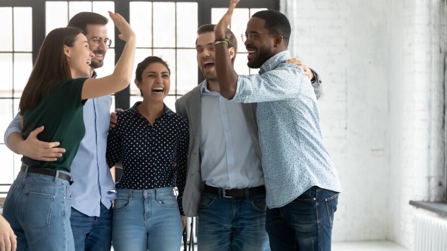 Five multi ethnic students or company employees accomplish project, exam pass, embracing feels excited celebrating common success giving high 5, gesture of unity racial equality and friendship concept