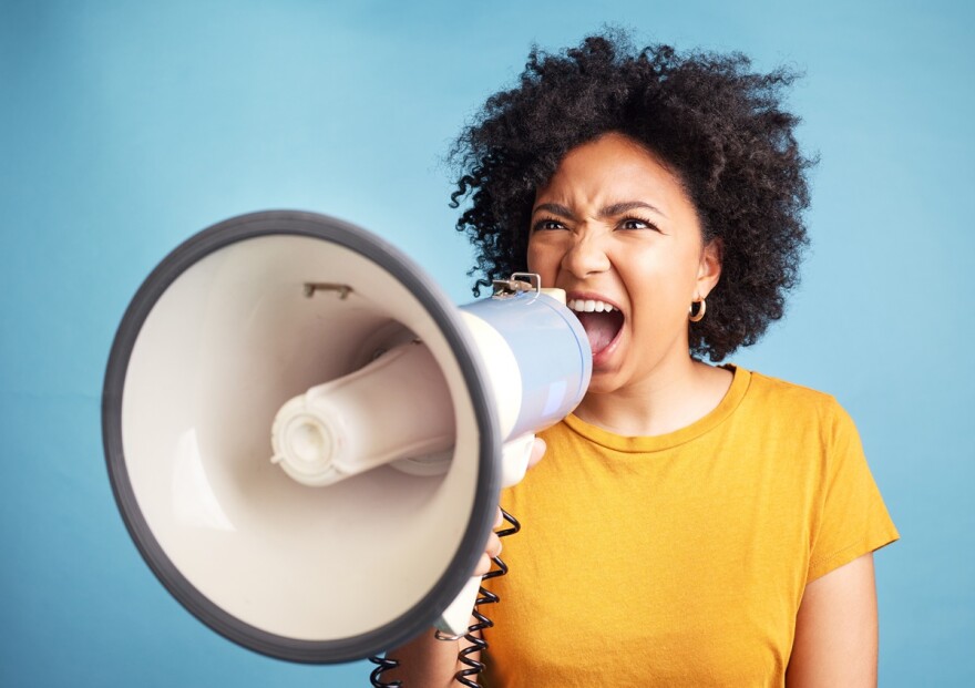 A woman is holding a bullhorn and yelling into it 