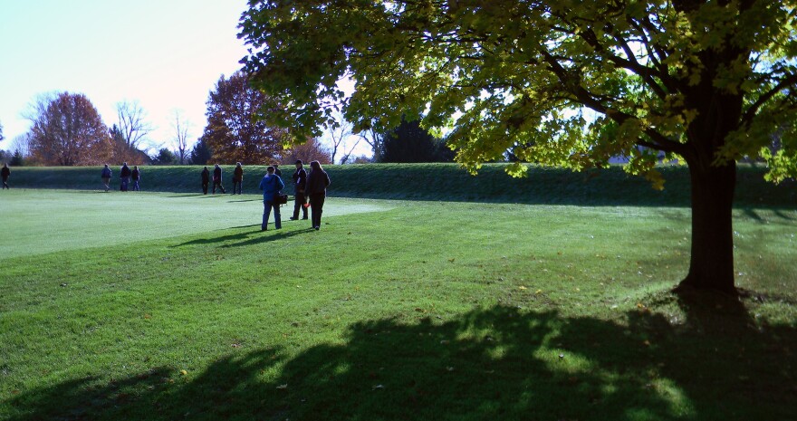 People walking inside of the walled earthworks enclosure. 