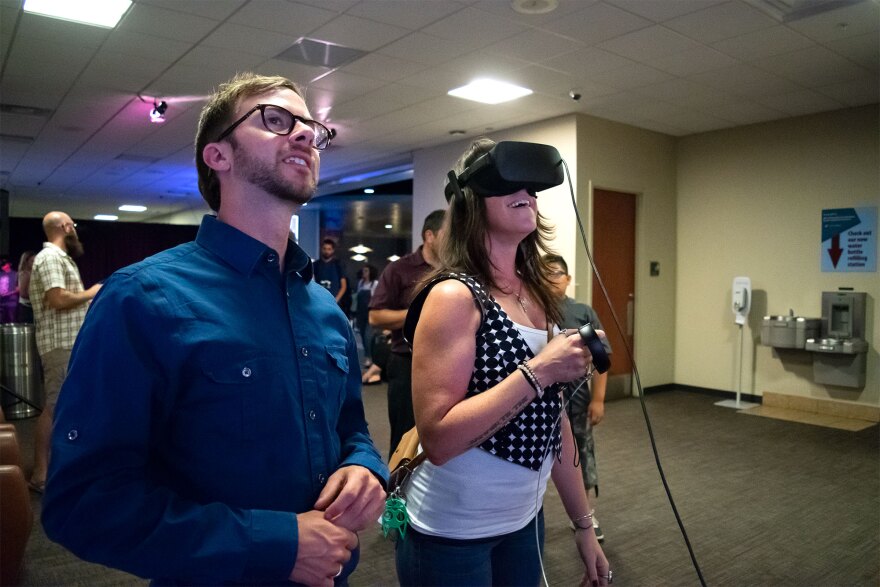 A man stands next to a woman wearing a headset in a crowded room. 