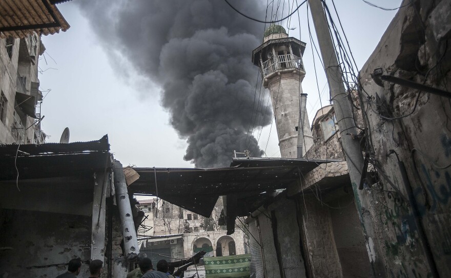 Rebel fighters watch as smoke rises after Syrian government forces fired an artillery round at a rebel position during heavy clashes in the Jedida district of Aleppo, Syria, on Sun., Nov. 4.