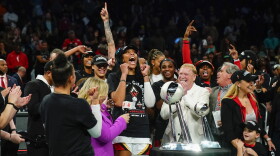 Las Vegas Aces' A'ja Wilson and Mark Davis celebrate with teammates next to the trophy after Game 4 of a WNBA basketball final playoff series against the New York Liberty Wednesday, Oct. 18, 2023, in New York. The Aces won 70-69. (AP Photo/Frank Franklin II)