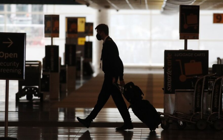 A lone airline crew member pulls his bags behind him as he walks through the baggage-claim area at Denver International Airport in Denver, amid the coronavirus outbreak.