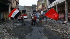 Anti-government protesters wave flags on Rasheed Street in Baghdad on Sunday.