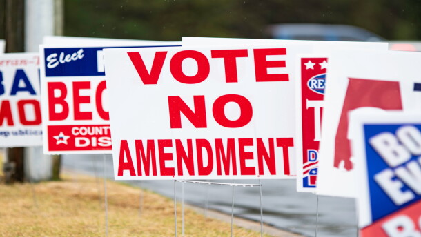A series of election yard signs with the center one reading "Vote No Amendment"