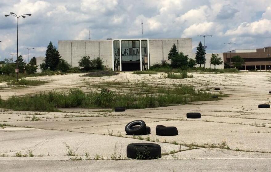 A vacant store and a weedy, tire-strewn parking lot at the former Rolling Acres Mall in Akron will be redeveloped into a four-story Amazon fulfillment center. [Khabir Bhatia / WKSU]