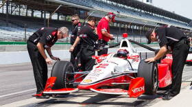 Team Penske crew members look over the No. 2 Verizon Chevrolet as Juan Pablo Montoya sits in the car.