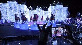 A visitor uses the top rail of a security gate to steady her smartphone as she records a video of a holiday display in front of 6215 Deloache Ave., in Dallas. The Preston Hollow residence grew in interest within the area and went viral due to it's spectacular display of lights and holiday decorations. Hundreds waited in long lines to experience the magical display which was photographed on December 23, 2034.