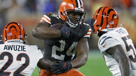 Cleveland Browns running back Nick Chubb (24) carries the ball with Cincinnati Bengals cornerback Chidobe Awuzie (22) and linebacker Germaine Pratt (57) defending during the first half of an NFL football game in Cleveland on Oct. 31, 2022.