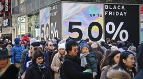 File - Crowds walk past a large store sign displaying a Black Friday discount in midtown Manhattan, Friday, Nov. 23, 2018, in New York. While Black Friday may no longer look like the crowd-filled, in-person mayhem that it was just decades ago — in large part due to the rising dependence on online shopping that was accelerated by the COVID-19 pandemic — the holiday sales event is still slated to attract millions of consumers. (AP Photo/Bebeto Matthews, File)