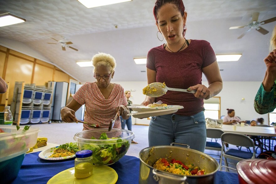 Genie Garda, right, and Amada Gregory grab food at the potluck in Dracut. Both women relocated from Puerto Rico after Maria. (Jesse Costa/WBUR)