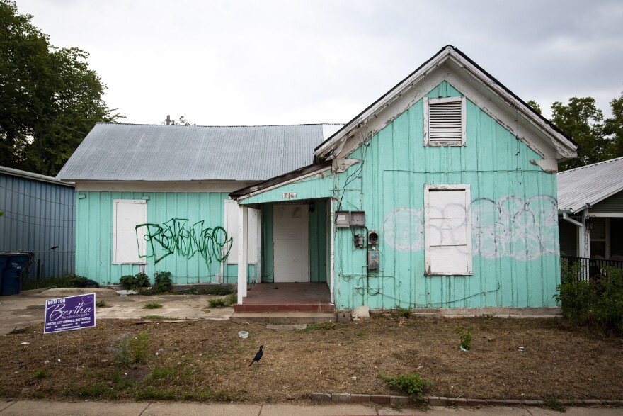 A teal house has graffiti on it.