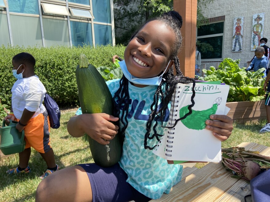 Young girl at the Urban Greenhouse holding a zucchini.