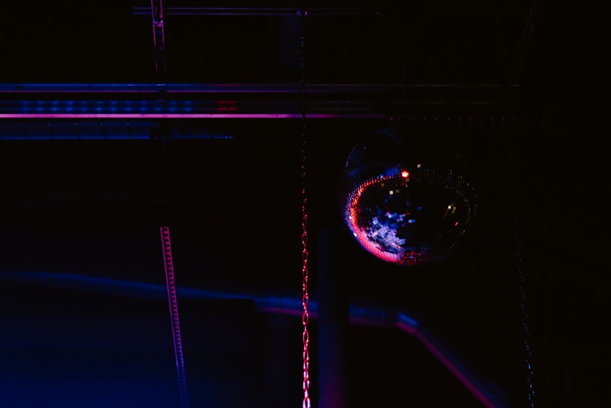 A disco ball hangs over the stage at xBk, a live music venue in Des Moines. It's washed in purple light. 