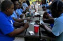 A family plays cards in a park during their family reunion.