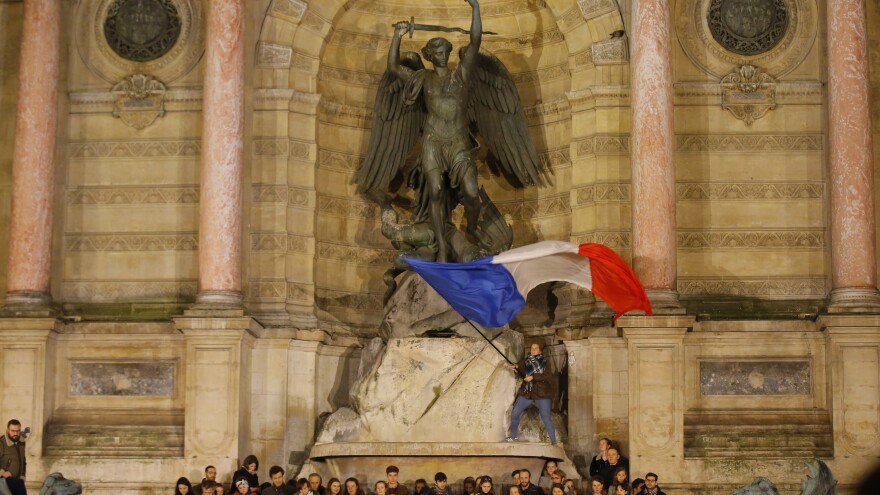 People attend a vigil in Paris on Tuesday near the fire-damaged cathedral.