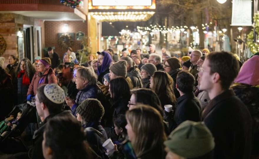 About 70 people watch as Jewish community leaders light a menorah near the Paramount Theater.