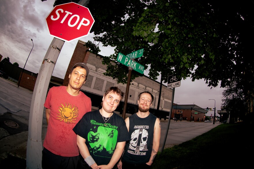 Three people standing in front of a STOP sign 