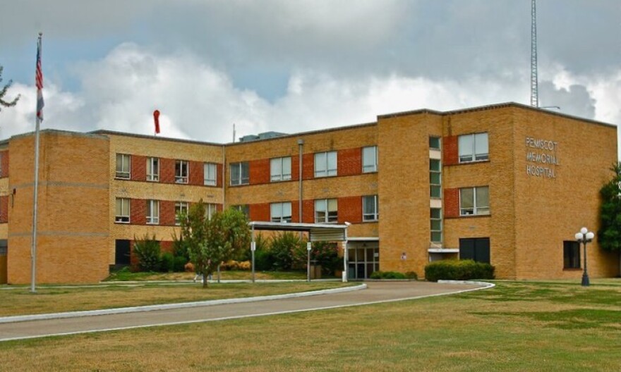 Large brown brick building with cloudy sky above and drive up to entrance.