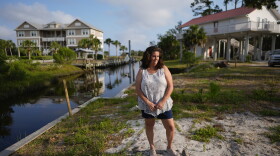 Lisa Bregenzer poses for a picture on the canal-side lot where her home stood until the passage of last year's Hurricane Idalia, Thursday, May 9, 2024, in Horseshoe Beach, Fla. In July, nearly a year after the storm that upended her and her husband's lives, Bregenzer has finally found hope. Her family was approved for a program that will help them build a new home, and if all goes as planned, they'll move into a stilted two-bedroom house on their lot by year's end.