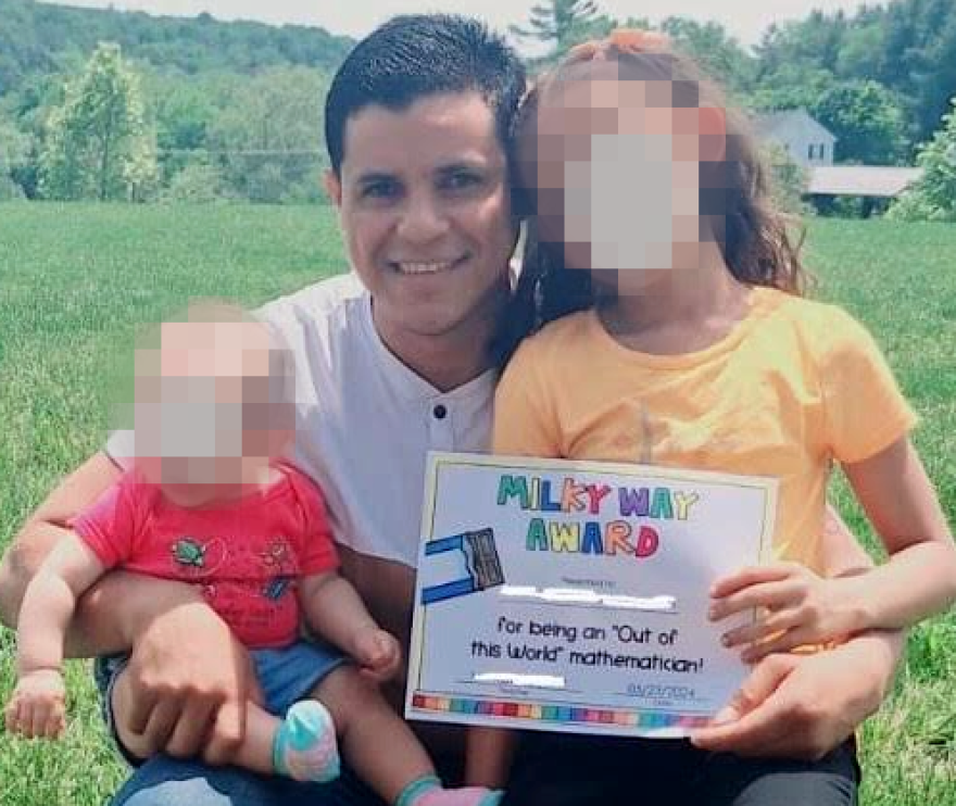 Olman, a father of two living in Staunton, Virginia, is pictured holding his kids — one of whom displays a math award from school.