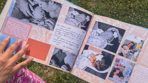 a baby scrapbook with a person's manicured hand in the photo