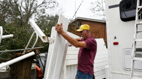 Curt Brown picks up debris left by Isaias around his RV home on Saturday, Oct. 10, 2026, in Milton, Fla. (AP Photo/Octavio Jones)