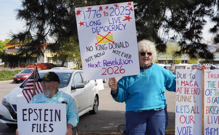 Older woman holding a large sign that says “1776 to 2025 long live democracy, no King Donald,” with additional handwritten messages.