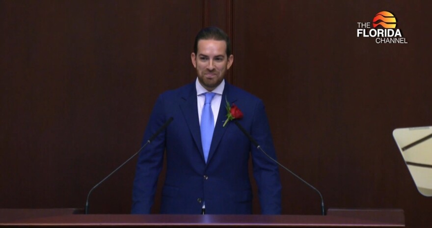 House Speaker Daniel Perez smiles behind a podium 